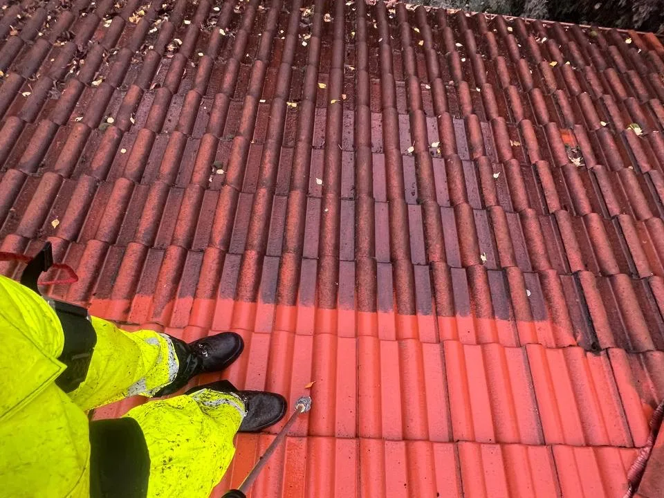 Umyty dach z czerwonej dachówki ceramicznej po usunięciu mchu i zabrudzeń