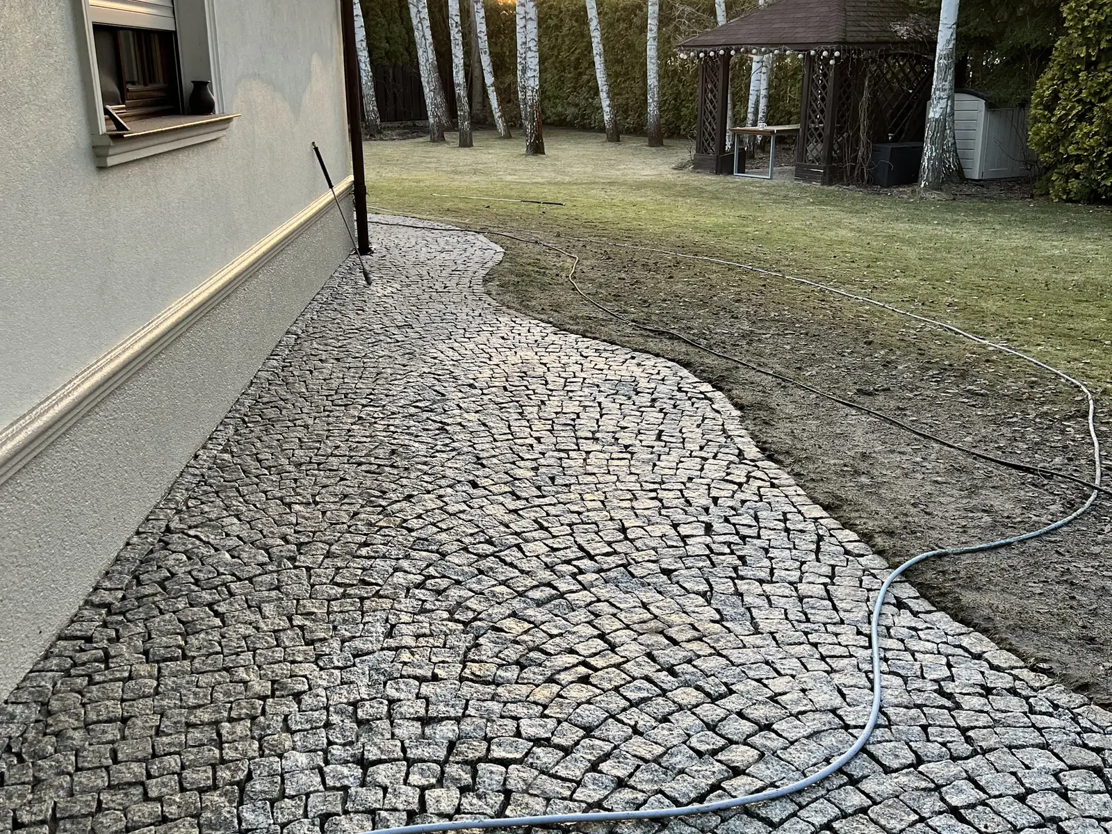 Ścieżka z kostki granitowej ułożona wzdłuż domu, widok po zakończeniu prac