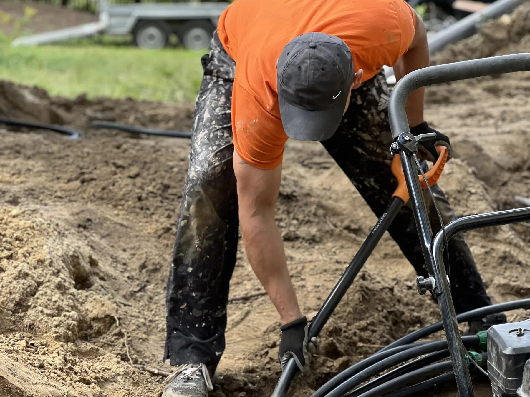 Pracownik KompletDom porządkuje teren i przewody instalacyjne na przekopanej działce przy domu