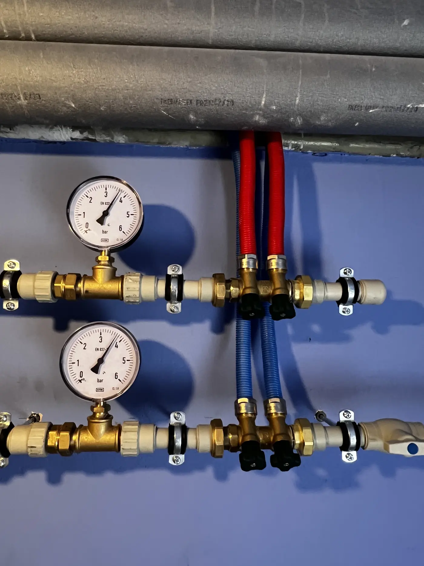 Rozdzielacz instalacji z dwoma manometrami, mosiężną armaturą i czerwono-niebieskimi przewodami w peszlu